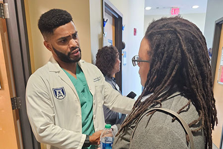 Kim standing and speaking to a taller male doctor in a hallway