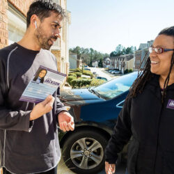 Kim standing in front of a male voter at his door with him holding a literature card of hers